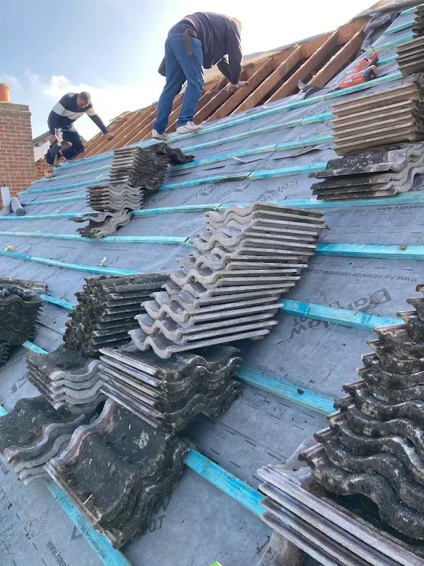 Alliance team stripping old tiles onto new membrane and battens during a re-roof