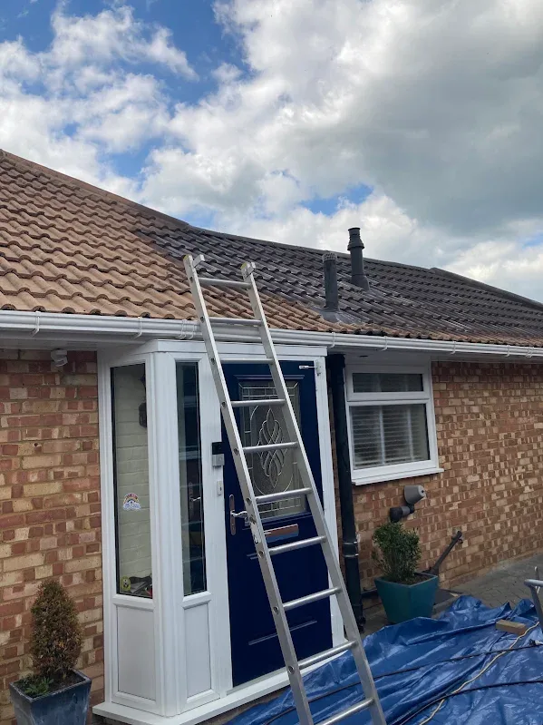 Ladder against a bungalow during roof work, with new white guttering