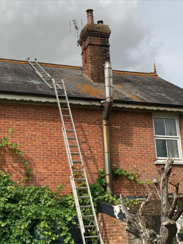 Ladder up to a brick chimney on a slate roof of a Victorian house