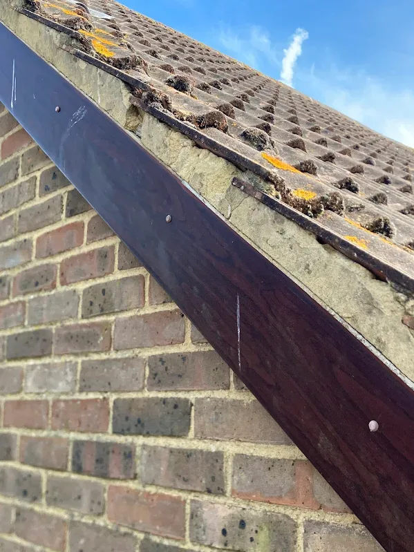 Worn bargeboard and mossy roof edge before roofline replacement