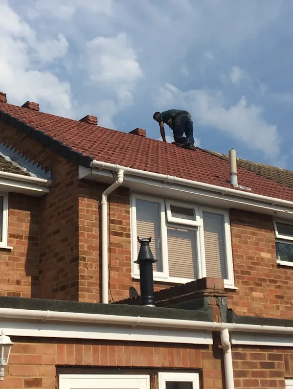 Emergency Roof Repairs: Roofer laying new red roof tiles during a re-roof in Kent