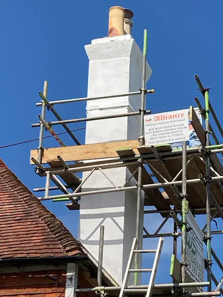 Chimney Repairs & Removals: Freshly rendered white chimney stack inside scaffolding with an Alliance banner