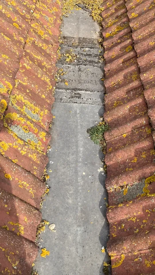Worn roof valley with moss and debris before repair