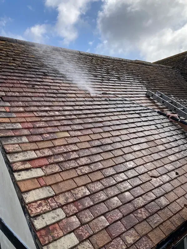 Roof Cleaning: Pressure washing moss from a tiled roof during roof cleaning in Kent